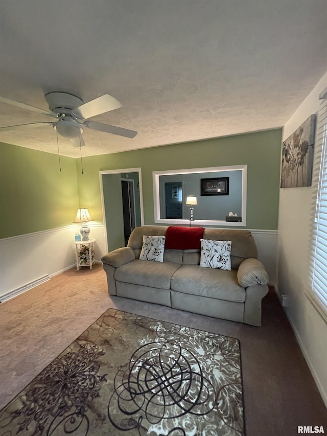 carpeted living area featuring baseboards, a baseboard heating unit, and a ceiling fan