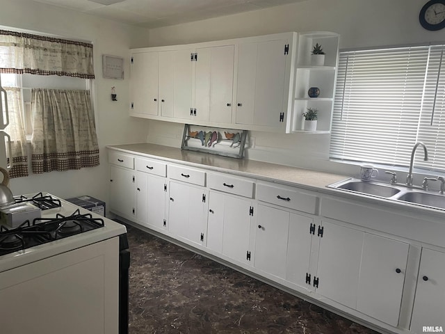 kitchen with white cabinets, open shelves, light countertops, and a sink