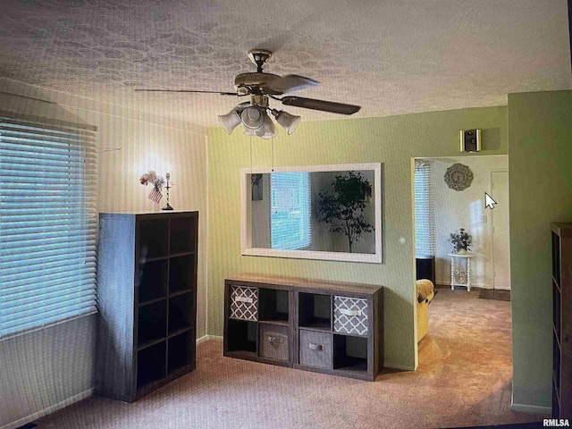 interior space featuring carpet flooring, a textured ceiling, wallpapered walls, and ceiling fan