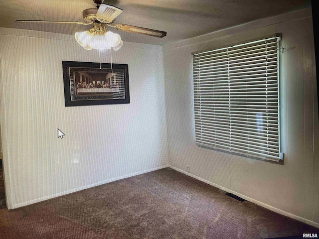 carpeted empty room featuring wallpapered walls, visible vents, baseboards, and ceiling fan