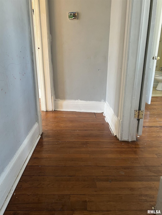 corridor with baseboards and hardwood / wood-style floors