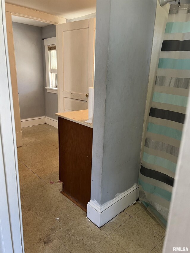 bathroom featuring curtained shower and baseboards