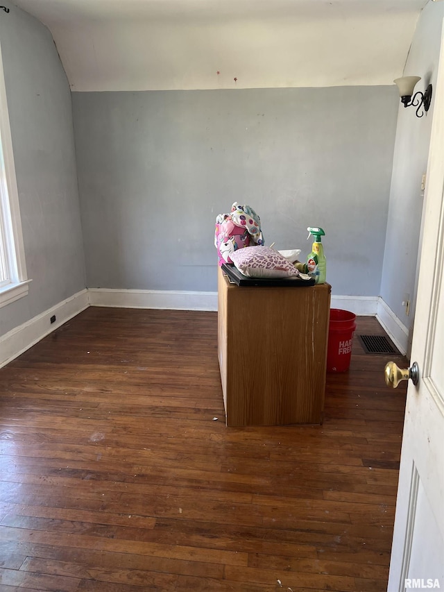 interior space with dark wood-type flooring, baseboards, and vaulted ceiling