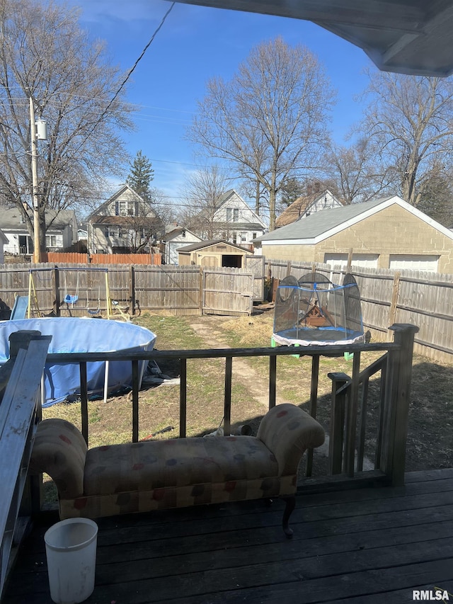 deck featuring a fenced backyard, a yard, and a trampoline