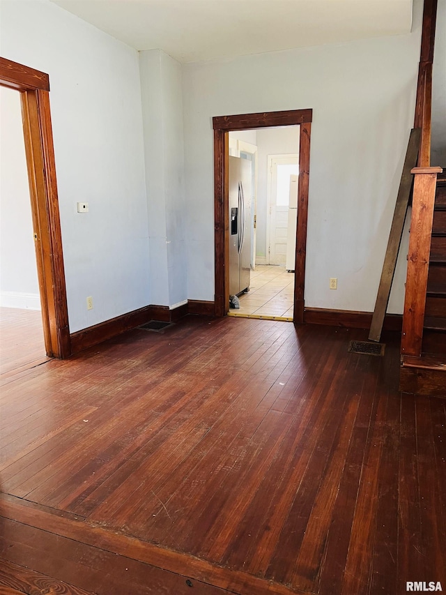 spare room with visible vents, baseboards, hardwood / wood-style floors, and stairs