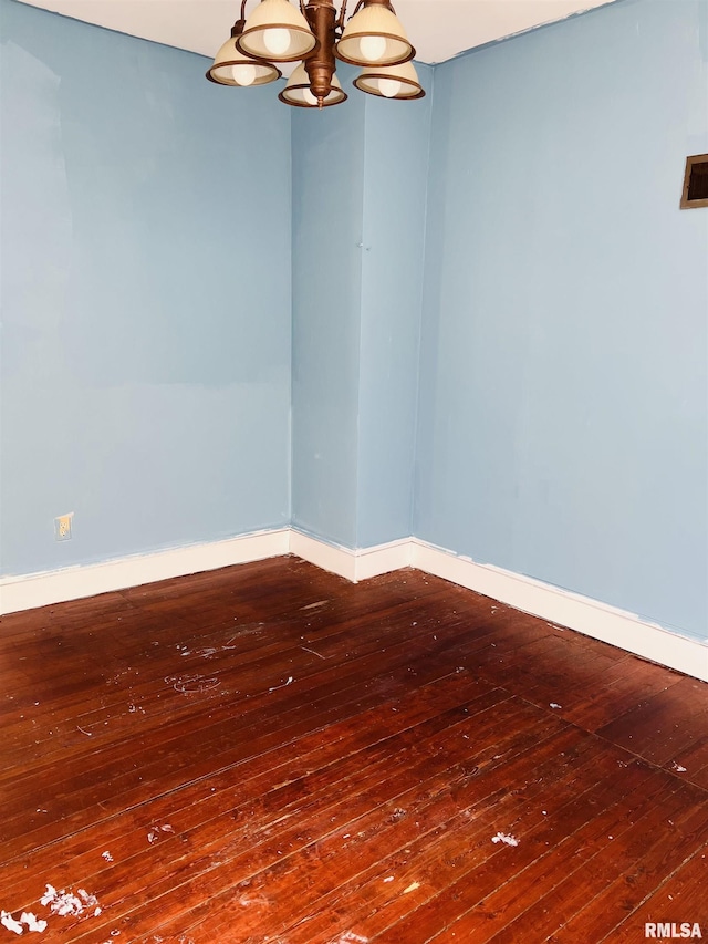 unfurnished room featuring baseboards, a notable chandelier, and hardwood / wood-style floors