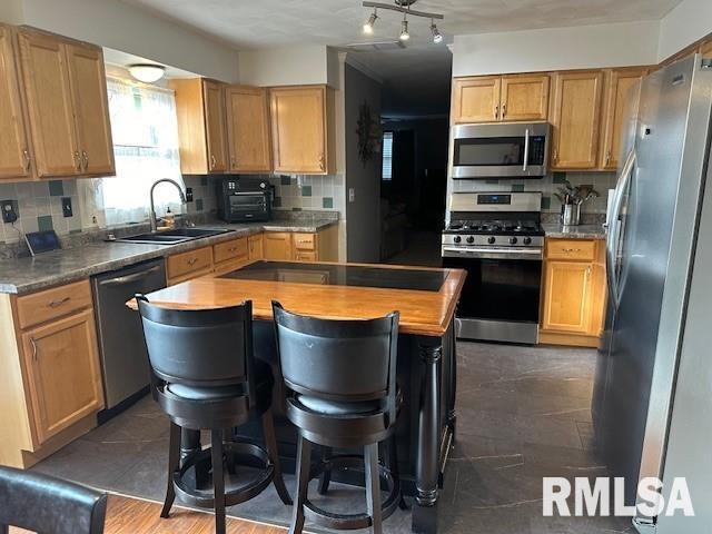 kitchen featuring a sink, stainless steel appliances, a center island, and decorative backsplash