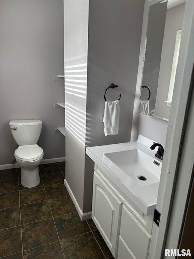 bathroom featuring toilet, vanity, and baseboards