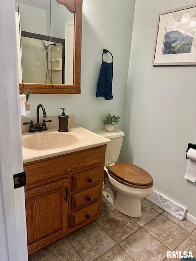 bathroom with vanity, a shower with shower door, toilet, and visible vents