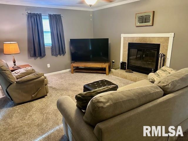 carpeted living area featuring a tiled fireplace, ceiling fan, baseboards, and ornamental molding