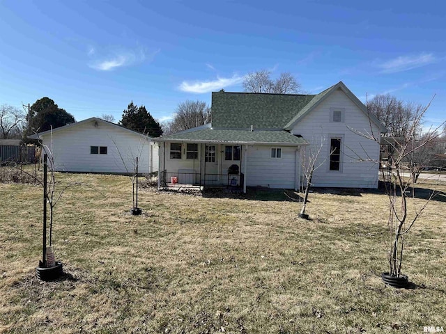 rear view of house featuring a lawn and roof with shingles