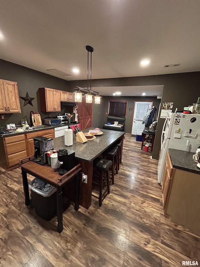 kitchen with visible vents, a center island, dark wood-type flooring, a breakfast bar, and hanging light fixtures