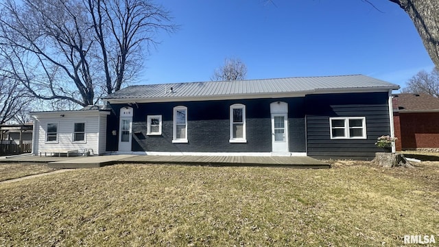 view of front of house featuring brick siding, covered porch, metal roof, and a front lawn