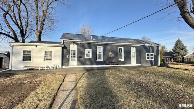 view of front of property with metal roof, brick siding, and a patio area