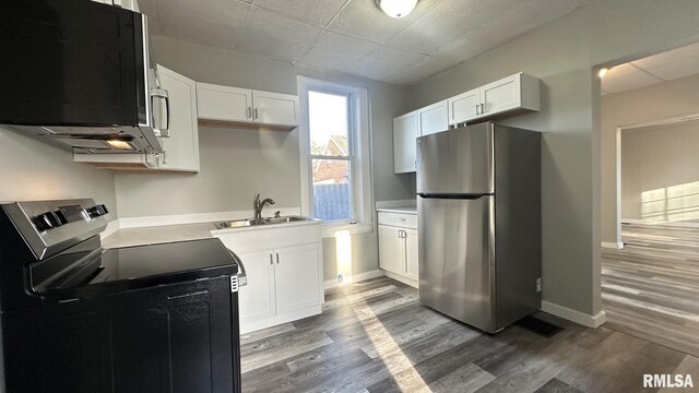 kitchen with a drop ceiling, white cabinetry, dark wood-style floors, and freestanding refrigerator