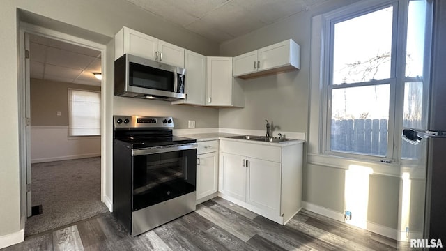 kitchen featuring dark wood-style flooring, a sink, light countertops, appliances with stainless steel finishes, and white cabinetry