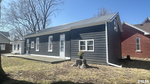 rear view of property with metal roof, brick siding, and a standing seam roof