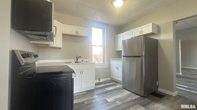 kitchen with a sink, range with electric stovetop, white cabinetry, freestanding refrigerator, and dark wood-style flooring