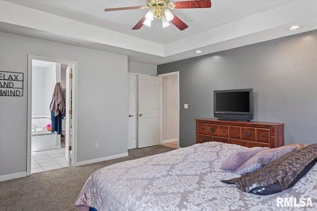 bedroom featuring a tray ceiling, baseboards, carpet floors, and ensuite bath