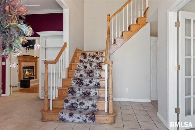 stairway with a tiled fireplace, tile patterned floors, and baseboards