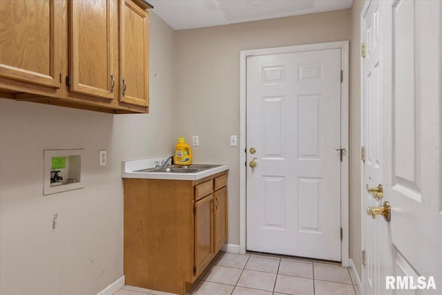 laundry area with baseboards, hookup for a washing machine, light tile patterned flooring, cabinet space, and a sink