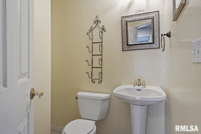 bathroom with toilet, baseboards, and a sink