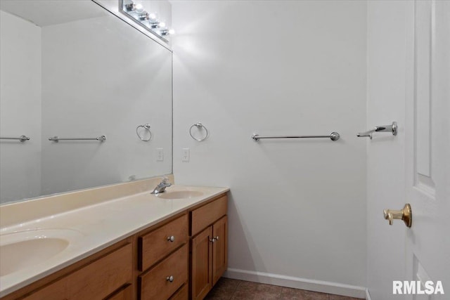 bathroom with double vanity, baseboards, tile patterned floors, and a sink