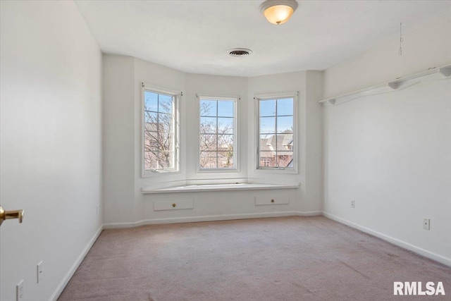 carpeted spare room featuring visible vents and baseboards