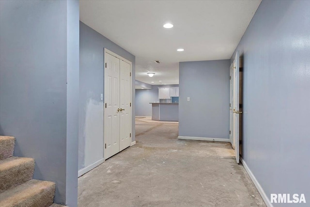 corridor with stairs, recessed lighting, baseboards, and concrete floors