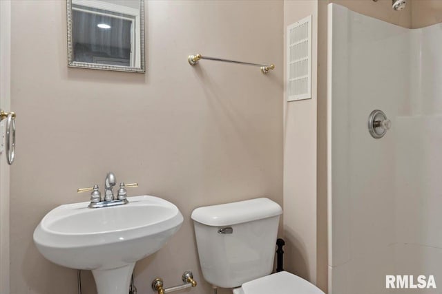 bathroom with toilet, walk in shower, and a sink