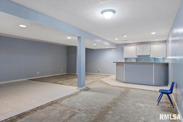 interior space with white cabinetry, baseboards, concrete flooring, recessed lighting, and a textured ceiling