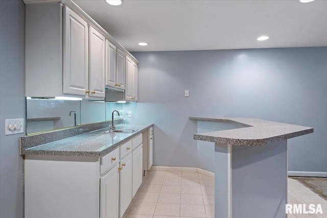 kitchen featuring a sink, baseboards, light tile patterned flooring, and recessed lighting