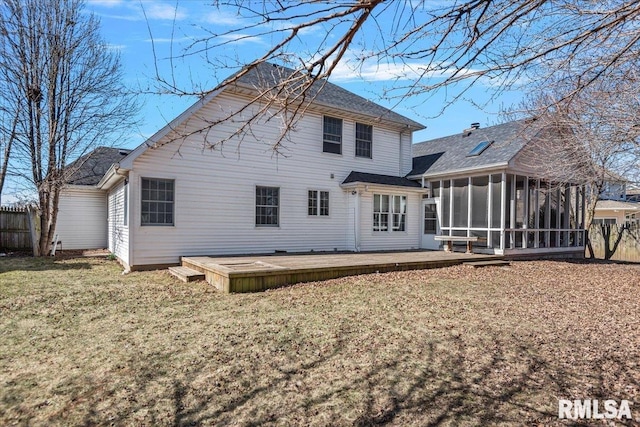 rear view of house with a yard, fence, a deck, and a sunroom