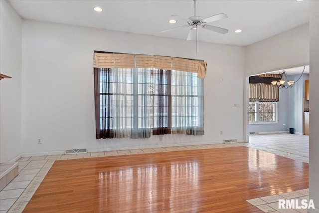 empty room with recessed lighting, visible vents, tile patterned floors, and ceiling fan with notable chandelier