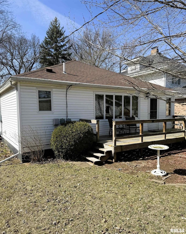 view of side of home featuring a lawn, roof with shingles, and a deck