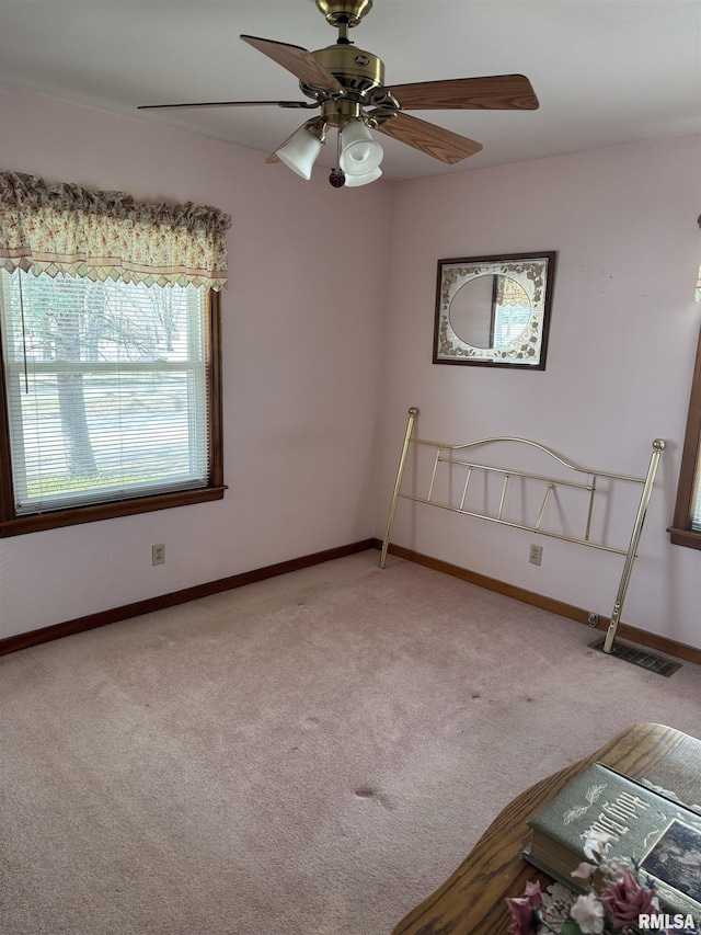 carpeted empty room with visible vents, ceiling fan, and baseboards