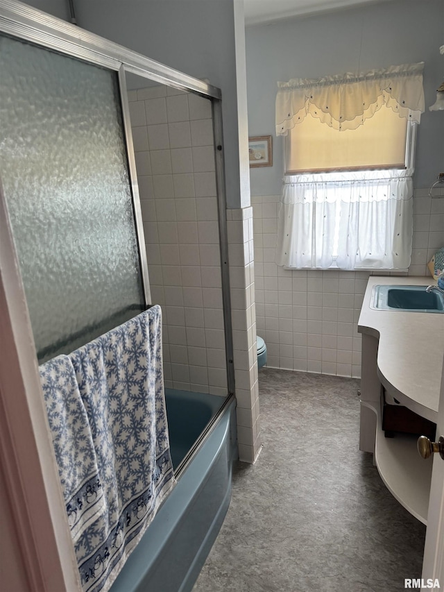 bathroom featuring enclosed tub / shower combo, toilet, tile walls, and vanity