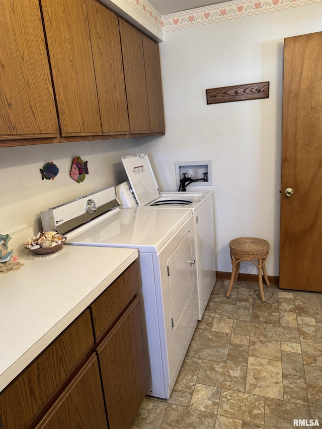 washroom with stone finish flooring, cabinet space, baseboards, and washing machine and clothes dryer