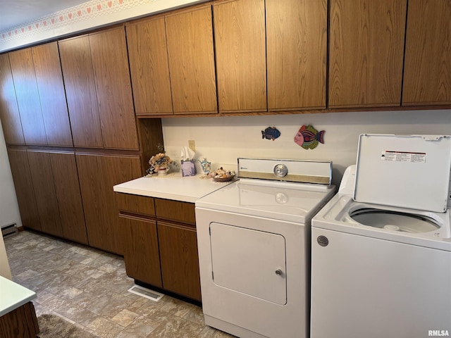 washroom with visible vents, cabinet space, and separate washer and dryer