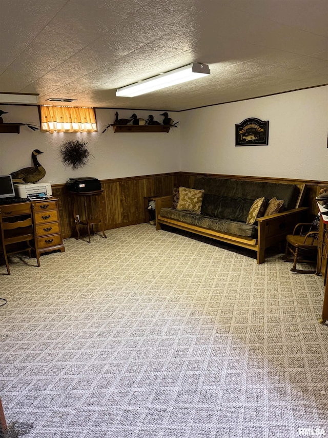 carpeted living room featuring a wainscoted wall, a textured ceiling, visible vents, and wood walls