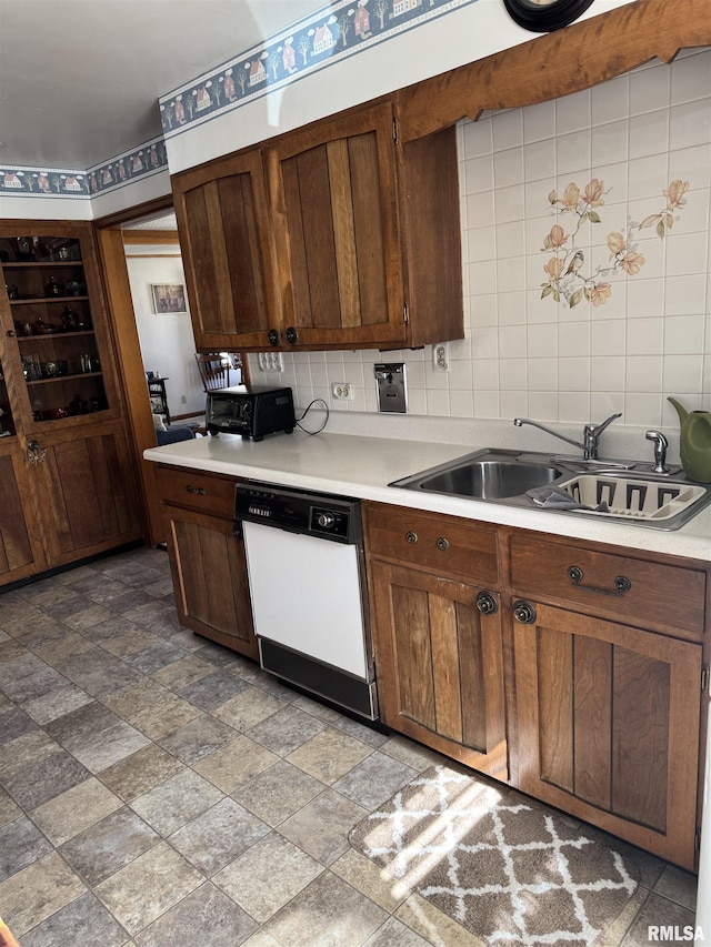 kitchen featuring decorative backsplash, dishwasher, light countertops, and a sink