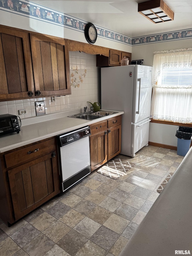 kitchen featuring tasteful backsplash, a toaster, light countertops, white appliances, and a sink