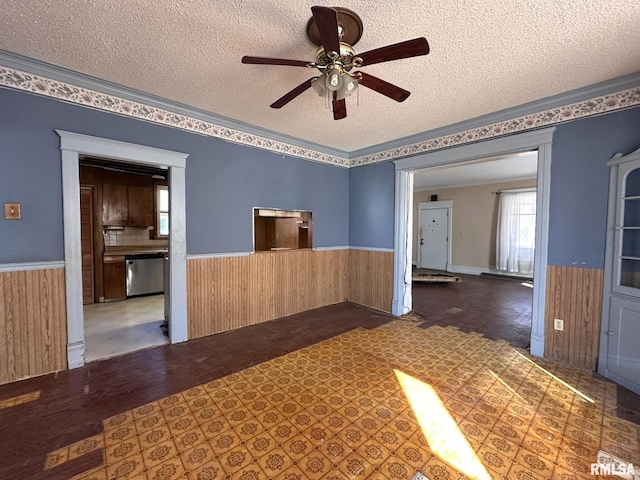 spare room with a wainscoted wall, wood walls, and a textured ceiling