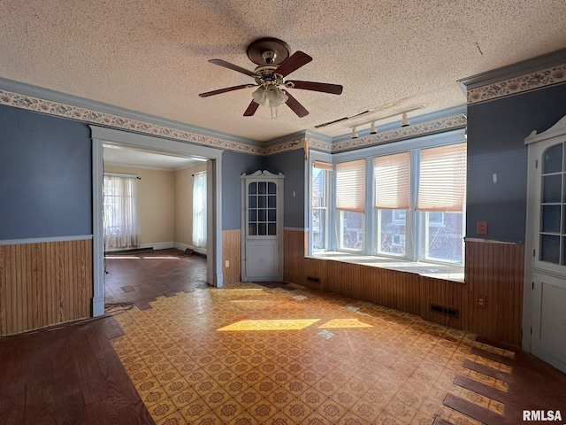 spare room with wooden walls, a wainscoted wall, and a textured ceiling