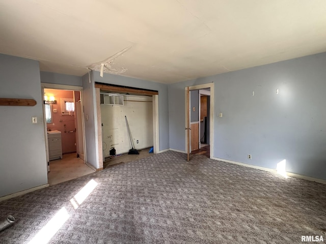 unfurnished bedroom featuring carpet flooring, baseboards, a closet, and ensuite bathroom