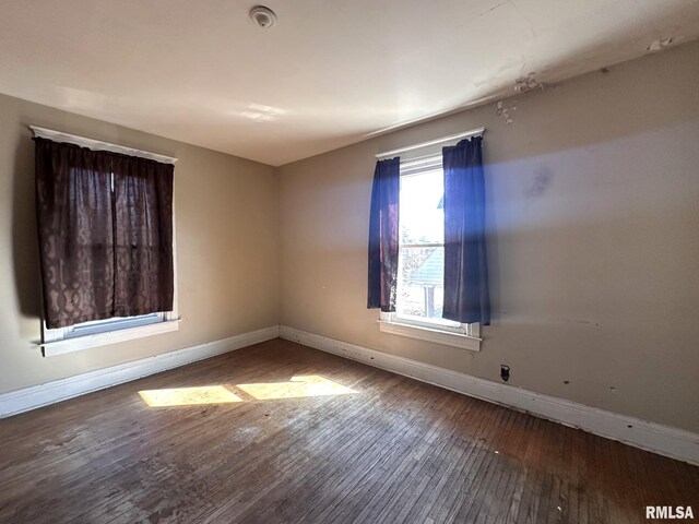 spare room featuring baseboards and hardwood / wood-style floors