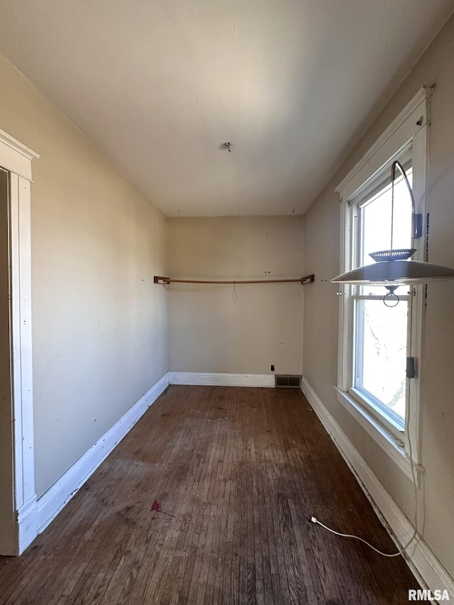 unfurnished room with wood finished floors, baseboards, and a wealth of natural light