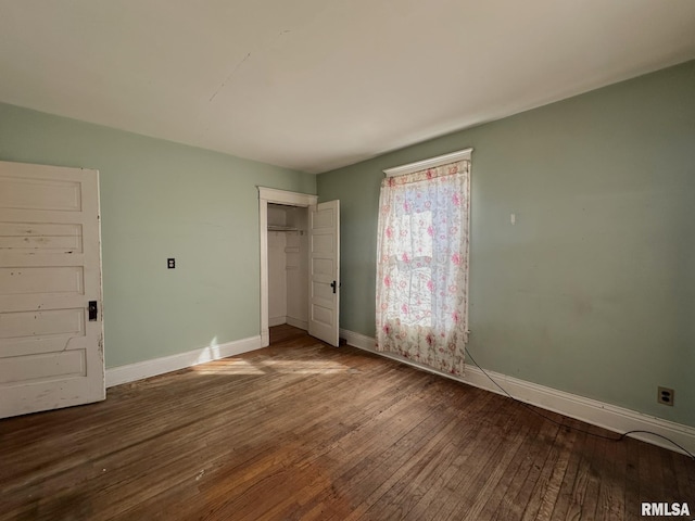 unfurnished bedroom with hardwood / wood-style flooring, baseboards, and a closet