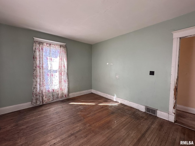 spare room with hardwood / wood-style floors, baseboards, and visible vents