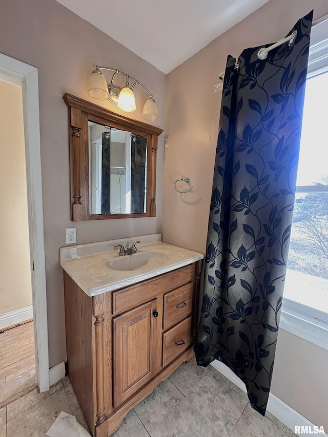 bathroom featuring a shower with shower curtain, baseboards, and vanity